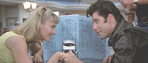 Grease: Danny and Sandy try for a moment of privacy in the malt shop.