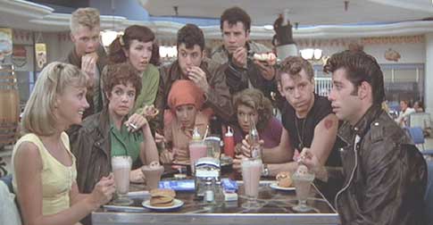 Grease: Sandy invites Danny to tea as the gang looks on.