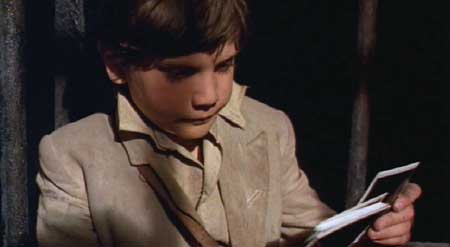 Time Bandits: Imprisoned in a hanging cage, Kevin dejectedly goes through his Polaroids.
